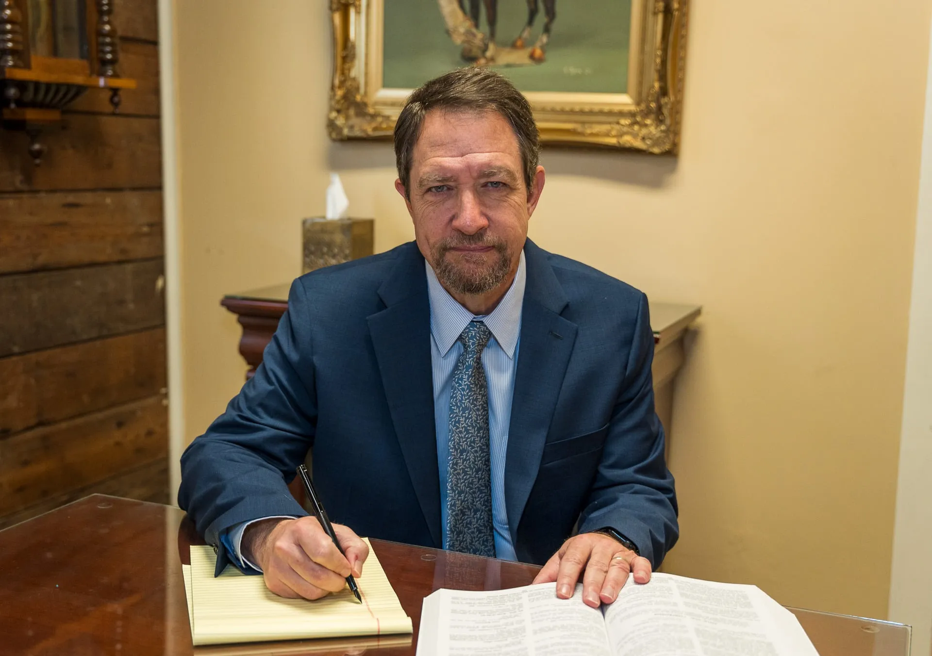 Richard D. Mere at his office table with a legal pad and an open law book.