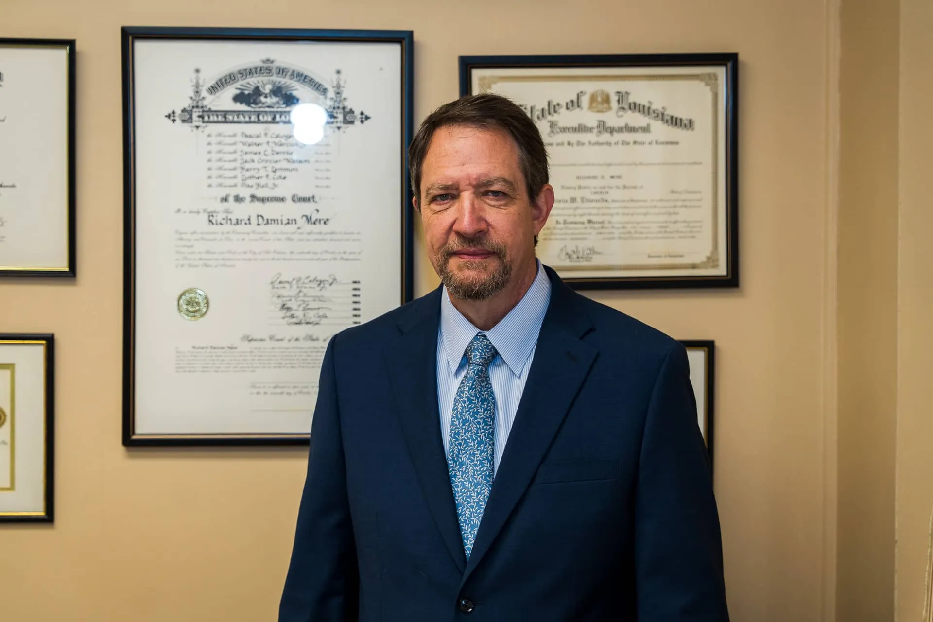 Richard D. Mere in his Lafayette office in front of his framed Louisiana Supreme Court admission and state certificates.