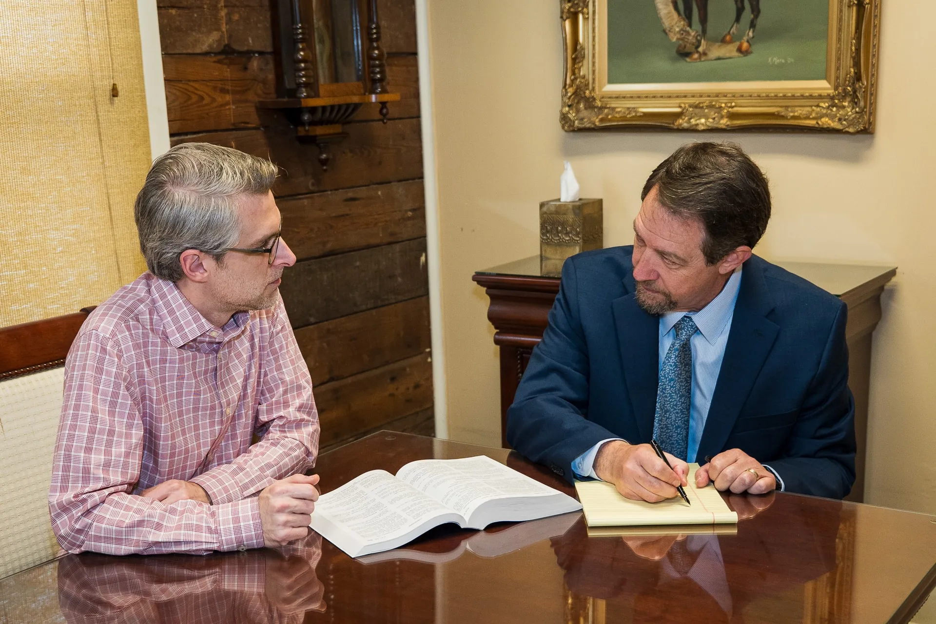 Richard D. Mere taking notes across the table from a client at his Lafayette office.