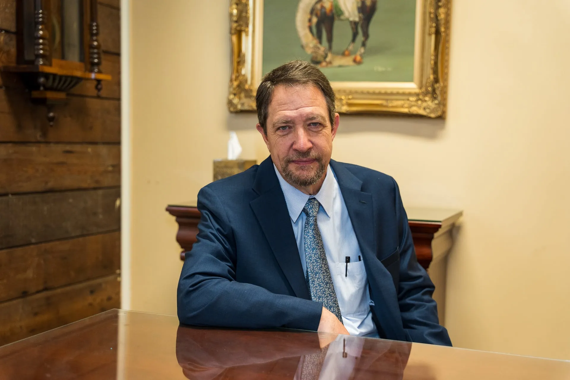 Richard D. Mere seated at his office table with his arm resting on the polished tabletop.