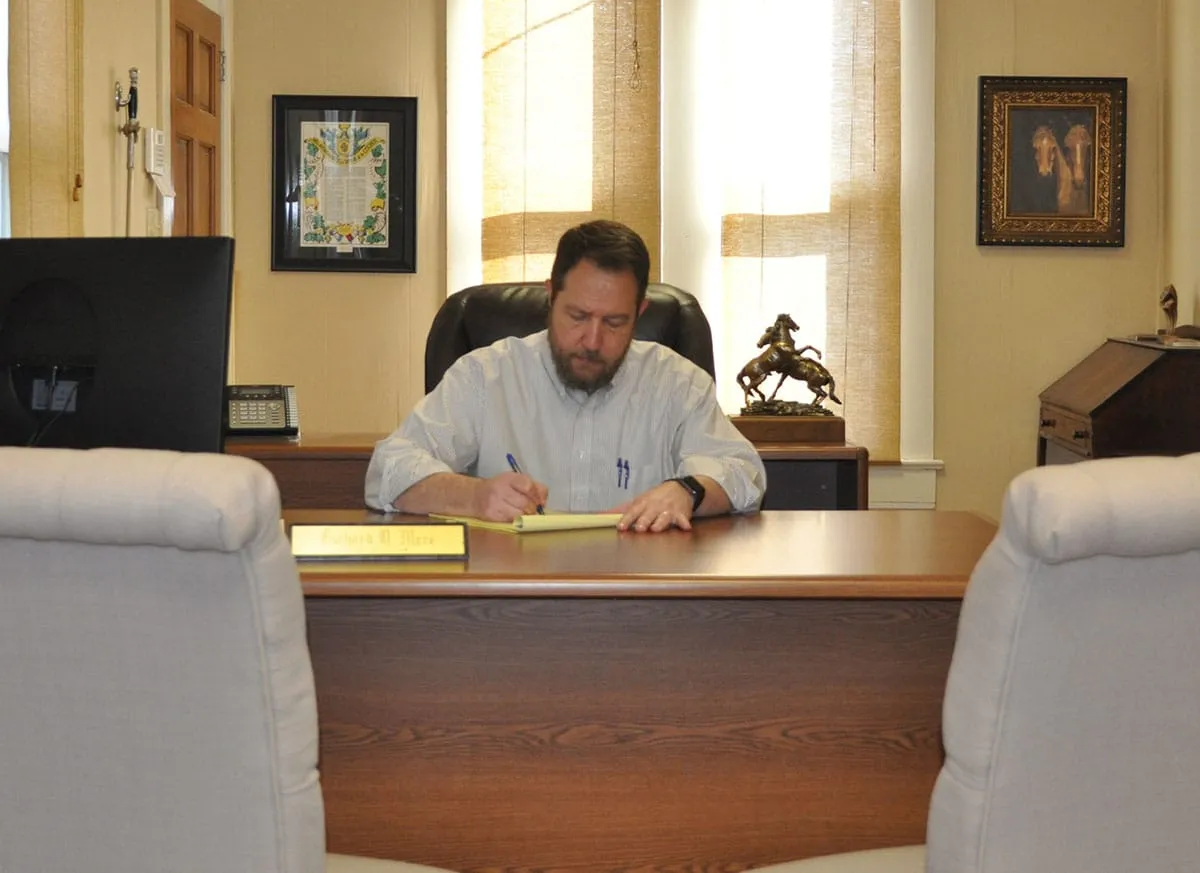 Richard D. Mere working at his desk, seen from the client chairs across his Lafayette office.